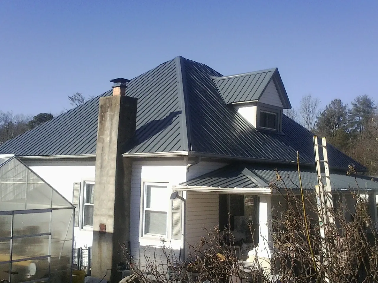 Dark blue standing seam metal roof on a white farmhouse with dormer — Slate & Tile Roof Repair by Roofing Brothers in Franktown