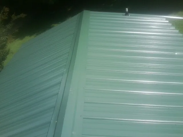 New green metal panels meeting at the ridge of a roof — Flat Roof Repair work by our crew in Franktown
