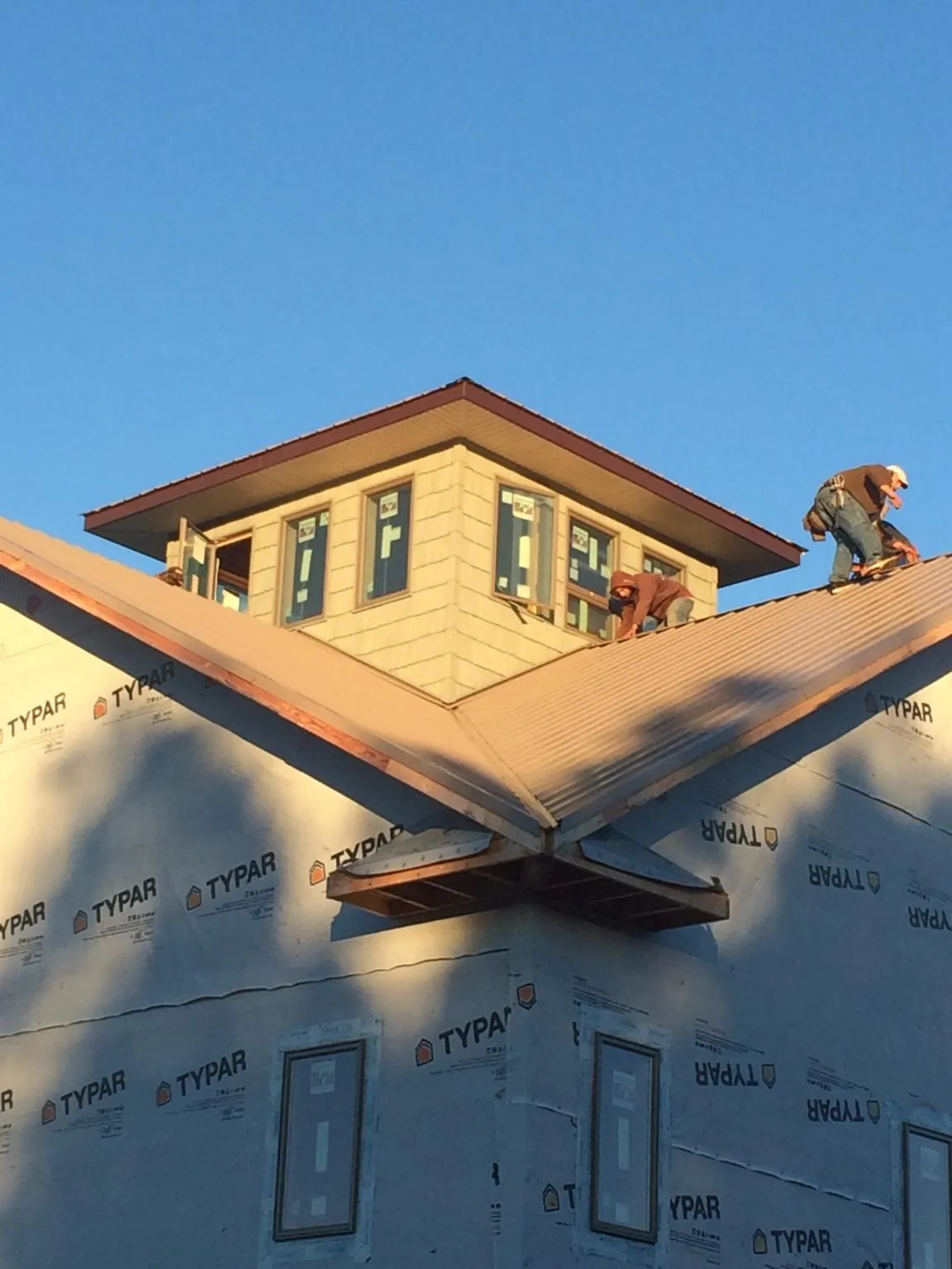 Roofers working around a rooftop cupola on a new metal roof at sunset — Roof Waterproofing in Franktown by Roofing Brothers